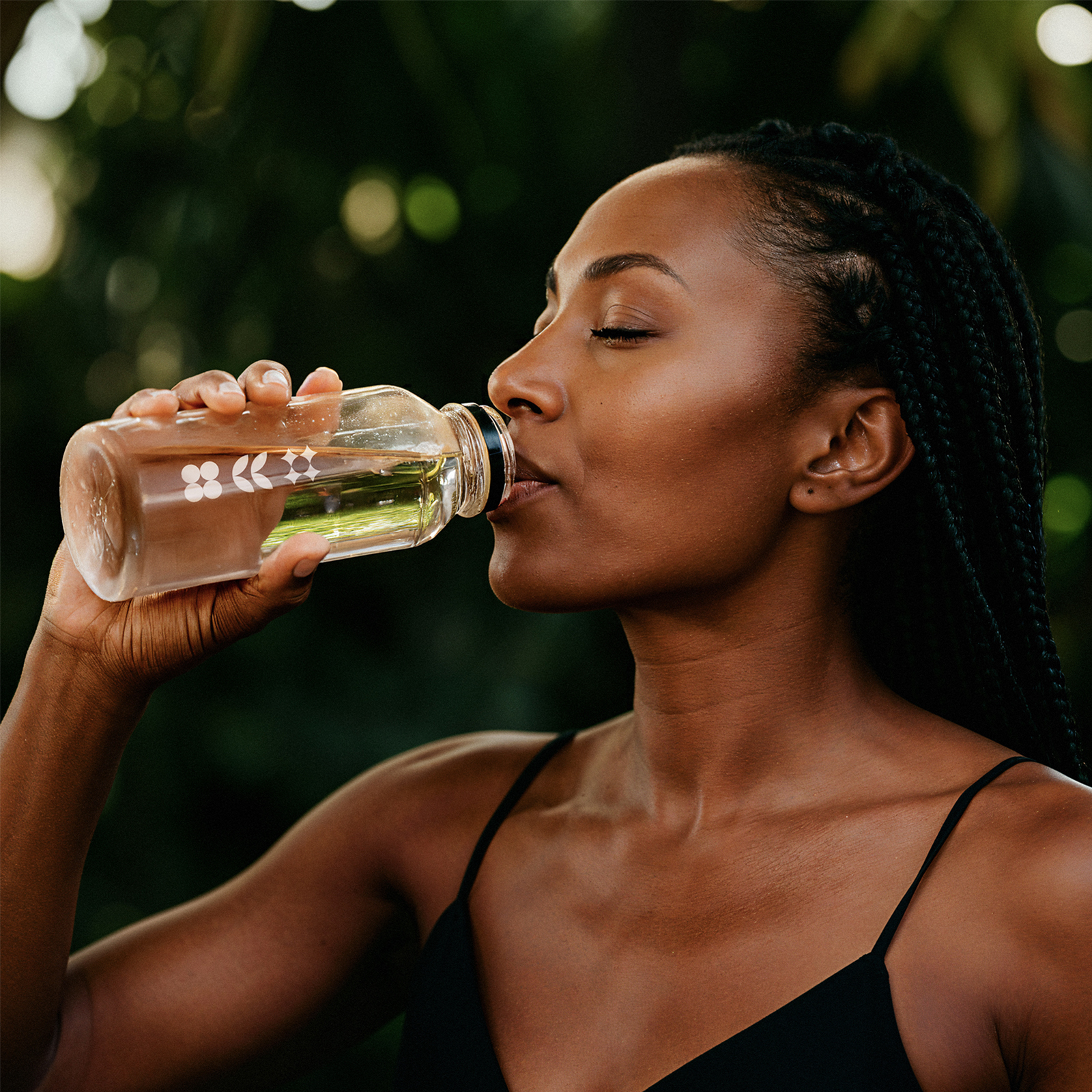 Une femme jeune et sportive boit du max₂o dans une gourde transparente